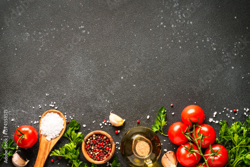 Food background with fresh vegetables, herbs and spices on black.