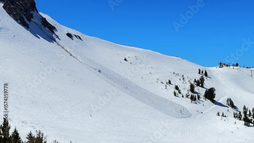 Inbound avalanche run off debris Spring winter sunny blue sky blue bird day main lodge Mammoth Mountain ski resort California aerial drone skiing snowboard groomed trail run spring corn snow pan left