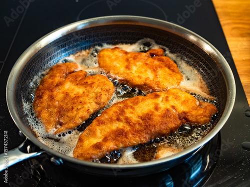Canvas Print Frying crispy breaded chicken cutlets in frying pan, close-up