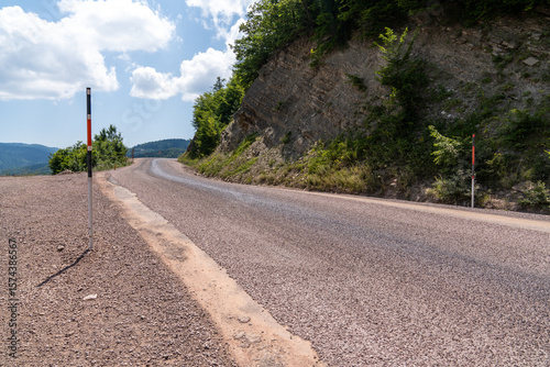 Winding road in the countryside in the mountains with blue sky and clouds.