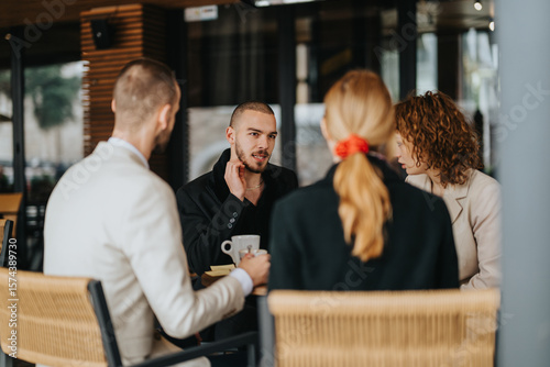 A group of four professionals discussing ideas while seated at an outdoor cafe table.