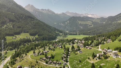 Summer Swiss Alpine Landscape with Picturesque Village, Traditional Chalets, and Green Hills Captured by Aerial Drone