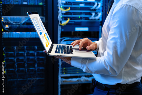 Technician working with laptop in server room technology data center
