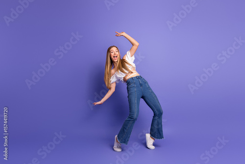 Wall Mural Stylish young woman making amusing gestures on a violet background, showcasing c