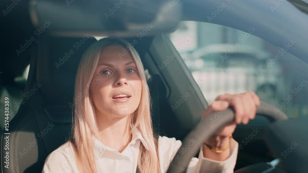 Confident blonde woman holding wheel with one hand while gazing ahead through windshield. Focusing on road or navigating traffic. Maintaining control and awareness during sunny daytime drive. Confident blonde woman holding wheel with one hand while gazing ahead through windshield. Focusing on road or navigating traffic. Maintaining control and awareness during sunny daytime drive.