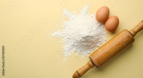 Flour eggs and rolling pin on a pale yellow background