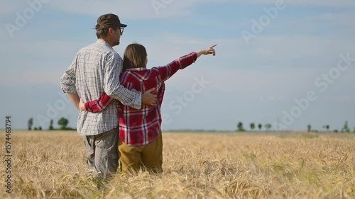 Male and female farm workers posing in ripe wheat plantation field ready for harvest, 4K