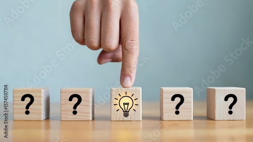 Concept of idea generation, hand pointing to lightbulb among question marks