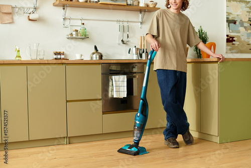 Handsome young man enjoying a peaceful moment while cleaning at home in a modern kitchen