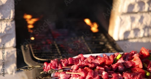 Skewered Meat in the Foreground with Barbecue Grill and Fire in the Background – 4K Slow Motion