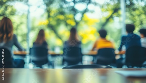 A group of people sitting at a table outdoors, blurred with a bright, natural background.