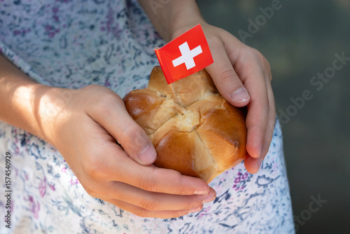 Swiss traditional August bread bun with a swiss flag in child hands