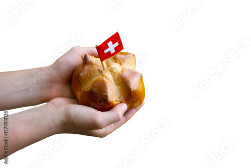 Child hands holding a national august bread bun with a swiss flag on isolated background with copy space