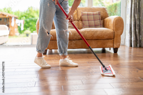 Tableau sur toile Cleaning hardwood floors in a cozy living room during a sunny afternoon with nat