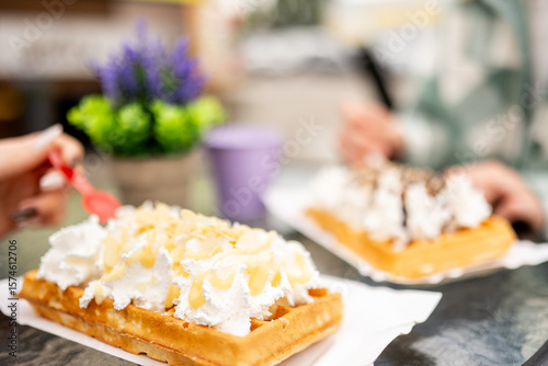 Two Girls Enjoying Belgian Waffles At A Cafe In A Close-Up, Soft-Focus Setting