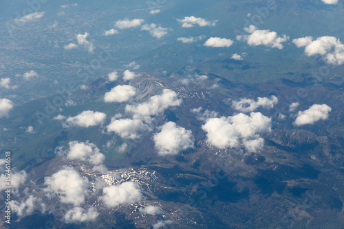The view of snow-capped mountain peaks through the clouds from 10,000 meters altitude