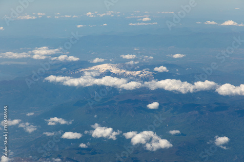 The view of snow-capped mountain peaks through the clouds from 10,000 meters altitude