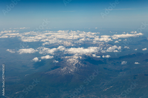 The view of snow-capped mountain peaks through the clouds from 10,000 meters altitude
