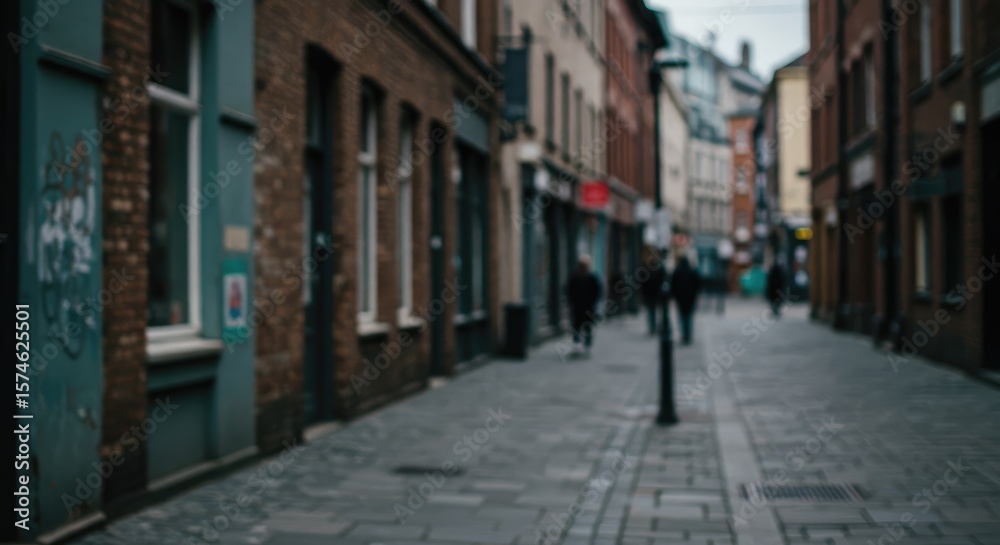 Fototapeta premium A blurred urban alleyway, featuring brick buildings and people walking