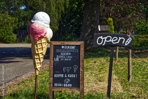 Giant ice cream cone and open sign welcoming customers to a dutch coffee shop selling homemade cheese, ice cream and more