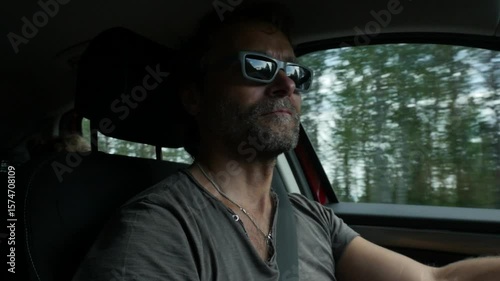Good looking young Caucasian man driving a car on a sunny day.  Bearded man driving a car on a road trip.