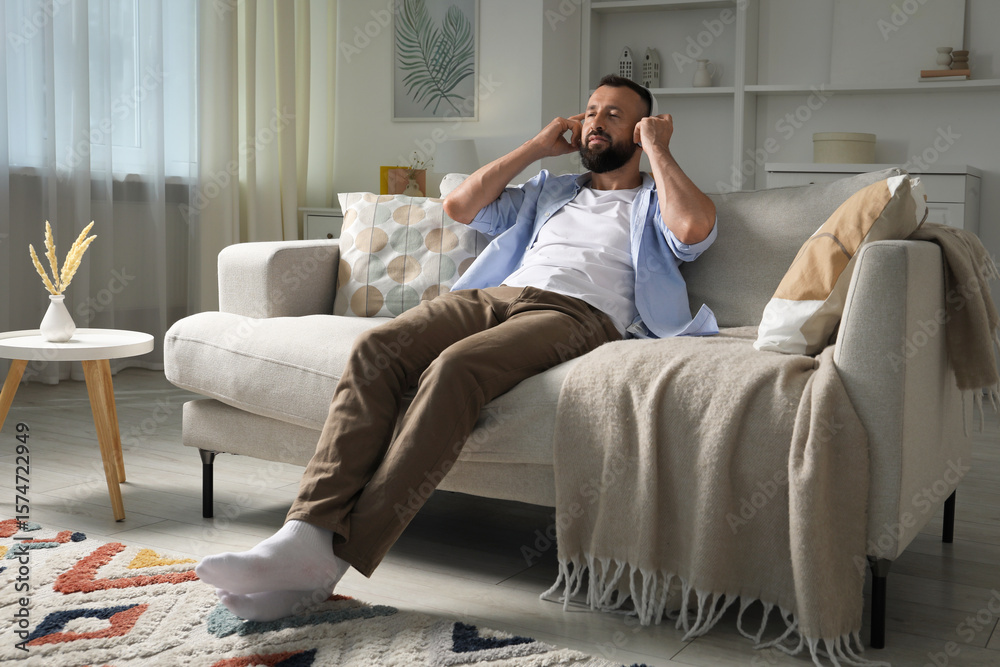 Obraz premium Harmony. Man listening to music in headphones on sofa at home