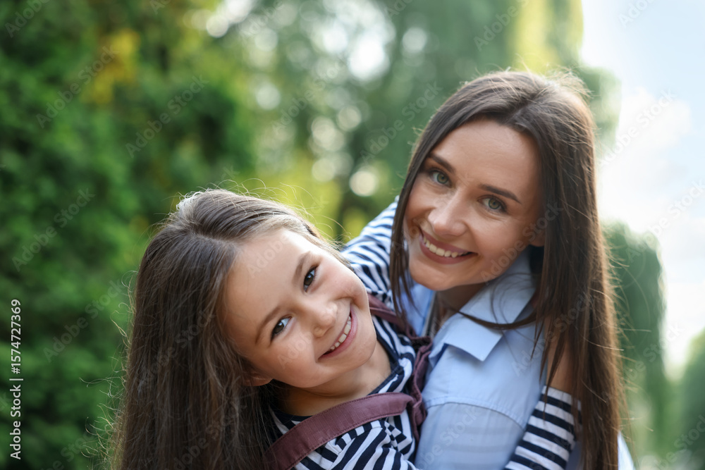 Fototapeta premium Family portrait of smiling mother and daughter in park