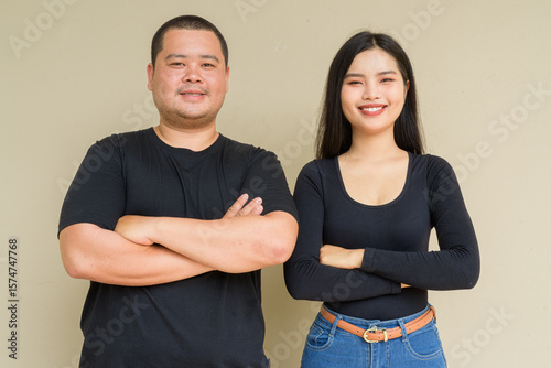 Portrait of young couple against plain wall background