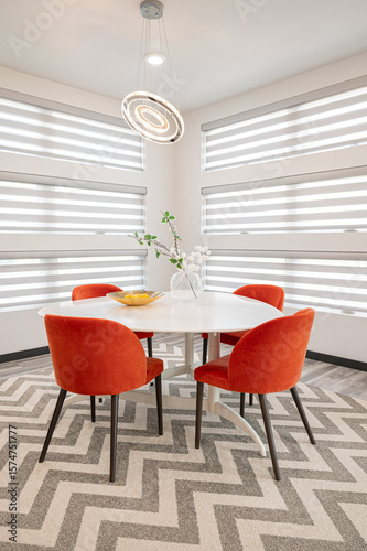 Modern dining area with orange chairs and striped blinds