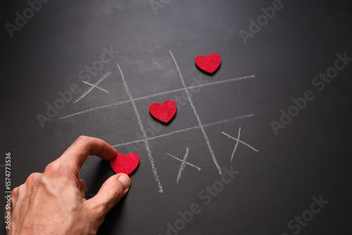 Konstfotografi Hand placing final heart in winning tic-tac-toe line drawn with chalk
