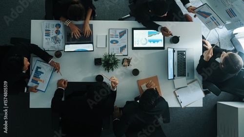 Bild auf Leinwand Top down aerial view of businesswoman pointing at financial graph on whiteboard while business team brainstorm marketing idea at meeting table with stock market statistic