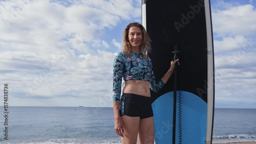Portrait of woman holding paddle surf board, ready for practicing stand up paddle sup surfing sport in the ocean. Smiling to camera