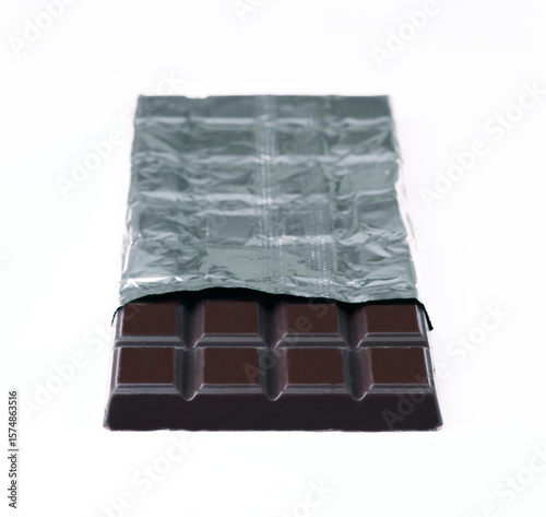 Dark chocolate bar partially wrapped in silver foil on white background