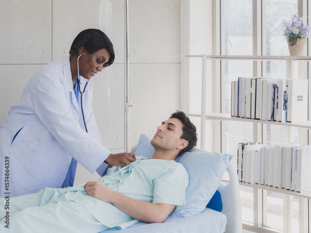 Obraz premium Caucasian patient man lying bed with woman doctor black people stand carer physical therapist two person talk help support and check treat sick person take care of your health in room hospital clinic