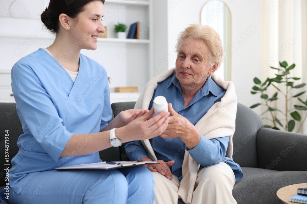 Fototapeta premium Nurse giving pills to senior woman indoors. Home health care service