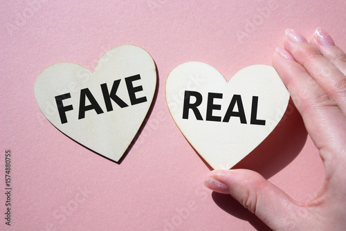 Real or Fake symbol. Concept word Real or Fake on wooden hearts. Beautiful pink background. Business and Real or Fake concept. Copy space