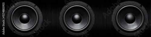 Three powerful audio speakers reproducing sound on black background