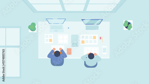 Overhead view of two people working at desks with computers and plants in a light blue room space