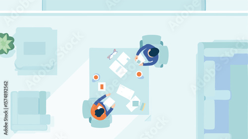 Overhead view of two people sitting at a table with papers and drinks in a brightly lit modern office space