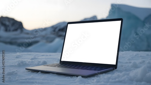 A laptop rests on a snowy, icy landscape with mountains in the background, showcasing technology in a cold, natural environment.