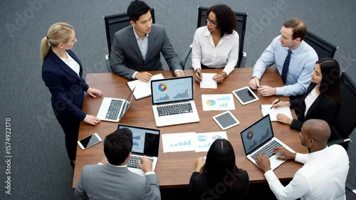 Diverse team of professionals analyzing business data and charts in a modern conference room meeting.