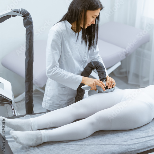 Therapist assisting woman in positioning correctly on massage table for LPG massage therapy in salon