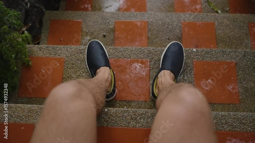 Man Sitting on Wet Stairs in Rain Wearing Black Slip-On Shoes Viewed From First-Person Angle, Slow Motion, Tropical Rainy Season and Relaxation Concept