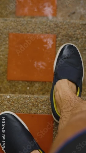 Vertical video. View of Wet Legs and Black Shoes on Stairs During Rain with Water Droplets Falling Around in Slow Motion, Tropical Downpour Concept