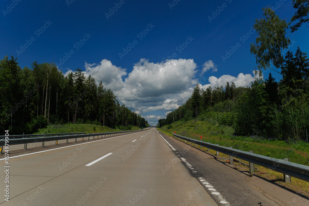 Naklejka premium Highway wide road, transport and blue sky with clouds on a summer day