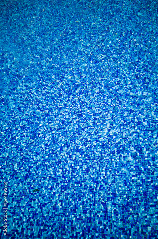 Obraz premium Bright blue mosaic tile texture under rippling pool water with sunlight reflections. Summer aquatic background with clear liquid surface.