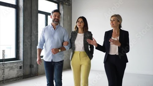 A real estate agent shows a couple a modern, spacious home in an urban setting, analyzing the space's features and potential.