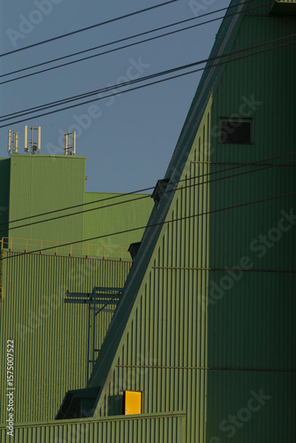 A unique green building featuring a bright yellow box located on the side, which stands out in the urban landscape