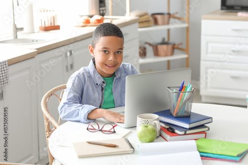Little African-American boy with laptop studying computer sciences online in ...