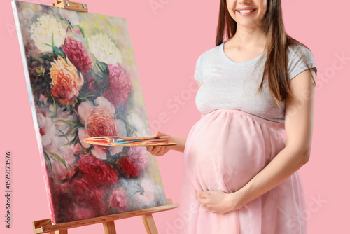 Young pregnant artist holdi...